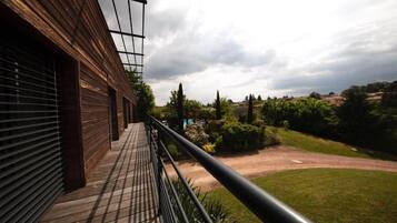 Een balkon met uitzicht op een aangelegde tuin en verre heuvels.