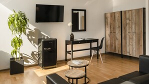 Un salon moderne avec un téléviseur à écran plat, un meuble en bois, un bureau, une chaise, un canapé et une plante en pot.
