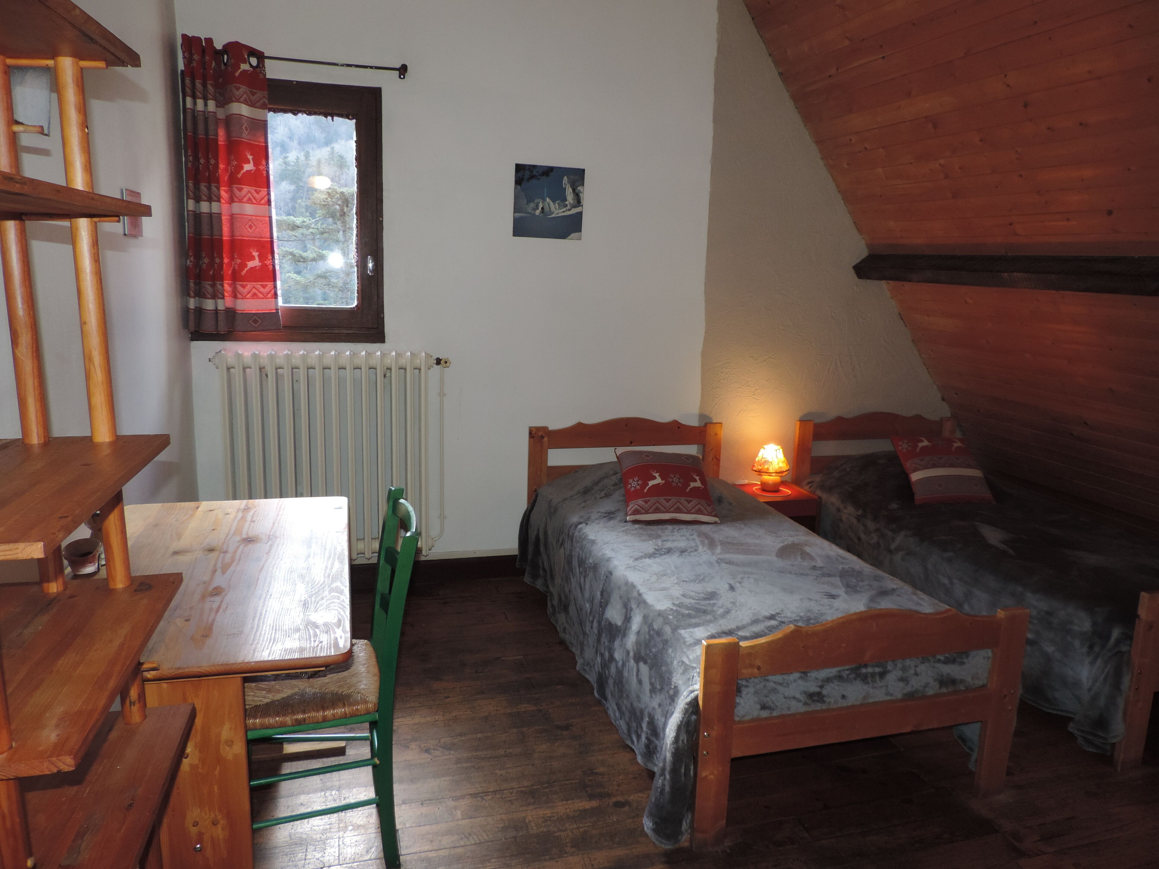 Una habitación pequeña y acogedora con una mesa de madera y dos camas individuales.