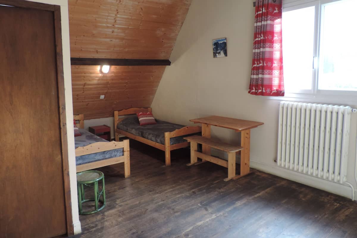 A small, cozy room with a sloped ceiling, a wooden bench, a small table, and a radiator.