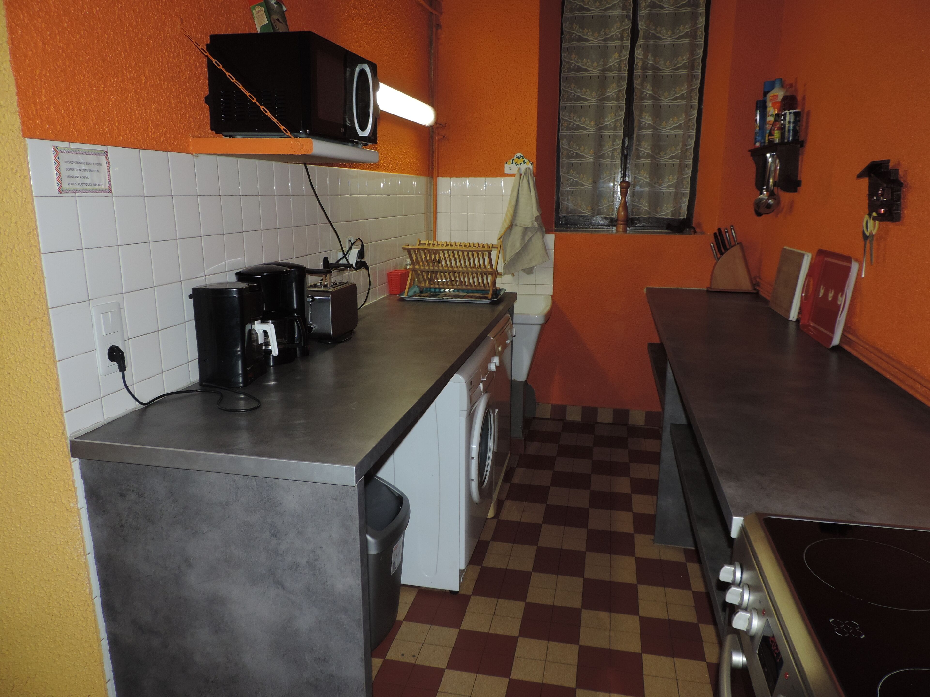 Een praktische keuken met een magnetron, koffiezetapparaat en een wasmachine.
