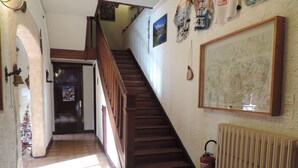A staircase with wooden railings leading to a second floor. A fire extinguisher is mounted on the wall beside the stairs. - Le Barbajou (Aragnouet)