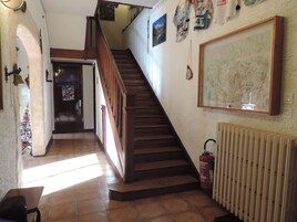 Una escalera con barandillas de madera que conduce a un segundo piso. Un extintor está colgado en la pared junto a las escaleras.
