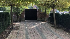 A paved driveway leading to a gated entrance with a brick wall and a metal gate. - Landgasthaus Fischer (Suthfeld)
