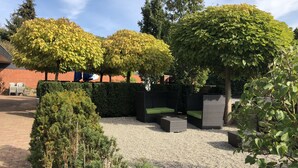 A garden with a seating area, a hedge, and a gravel path. - Landgasthaus Fischer (Suthfeld)