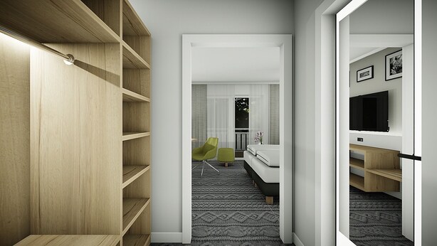 A modern hotel room with a walk-in closet, a bed, a TV, and a small seating area. - Landgasthaus Fischer (Suthfeld)