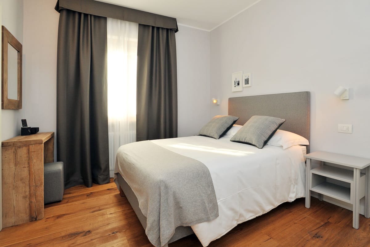 A neatly arranged bedroom with a bed, bedside table, and a small wooden bench.