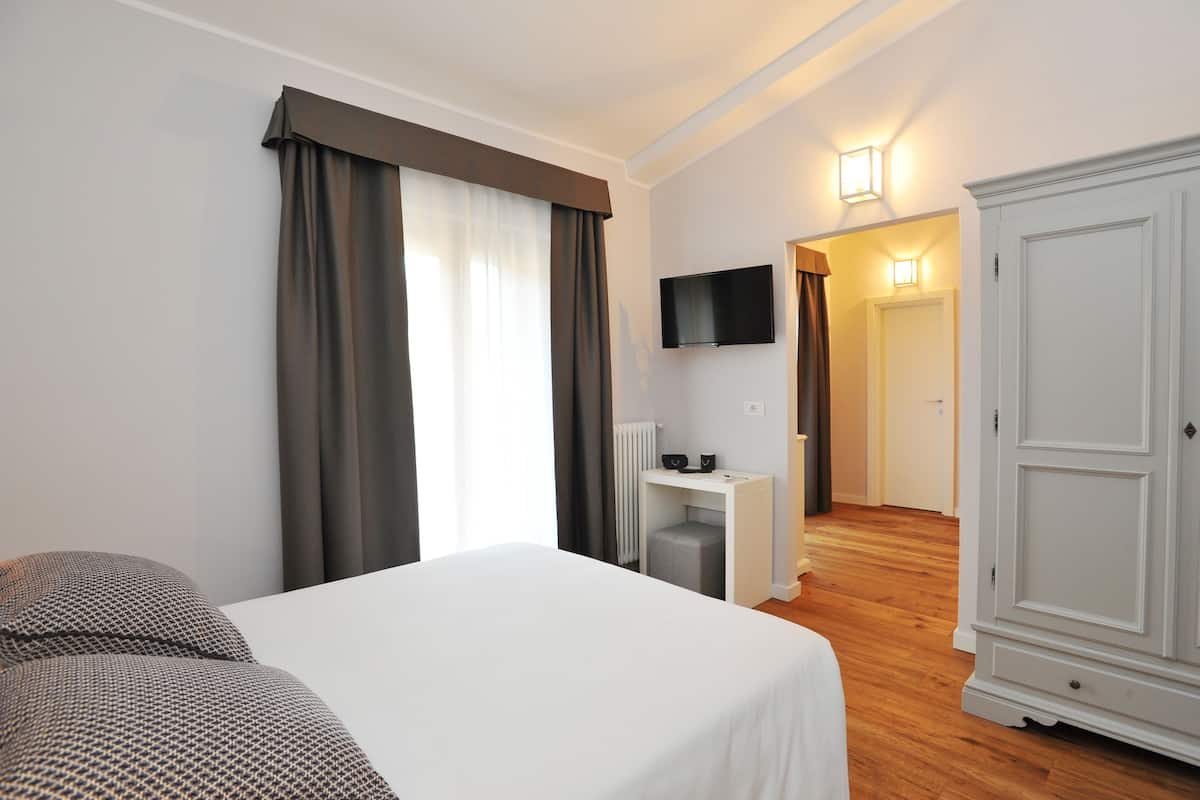 A hotel room with a bed, a desk, a television, and a wardrobe.
