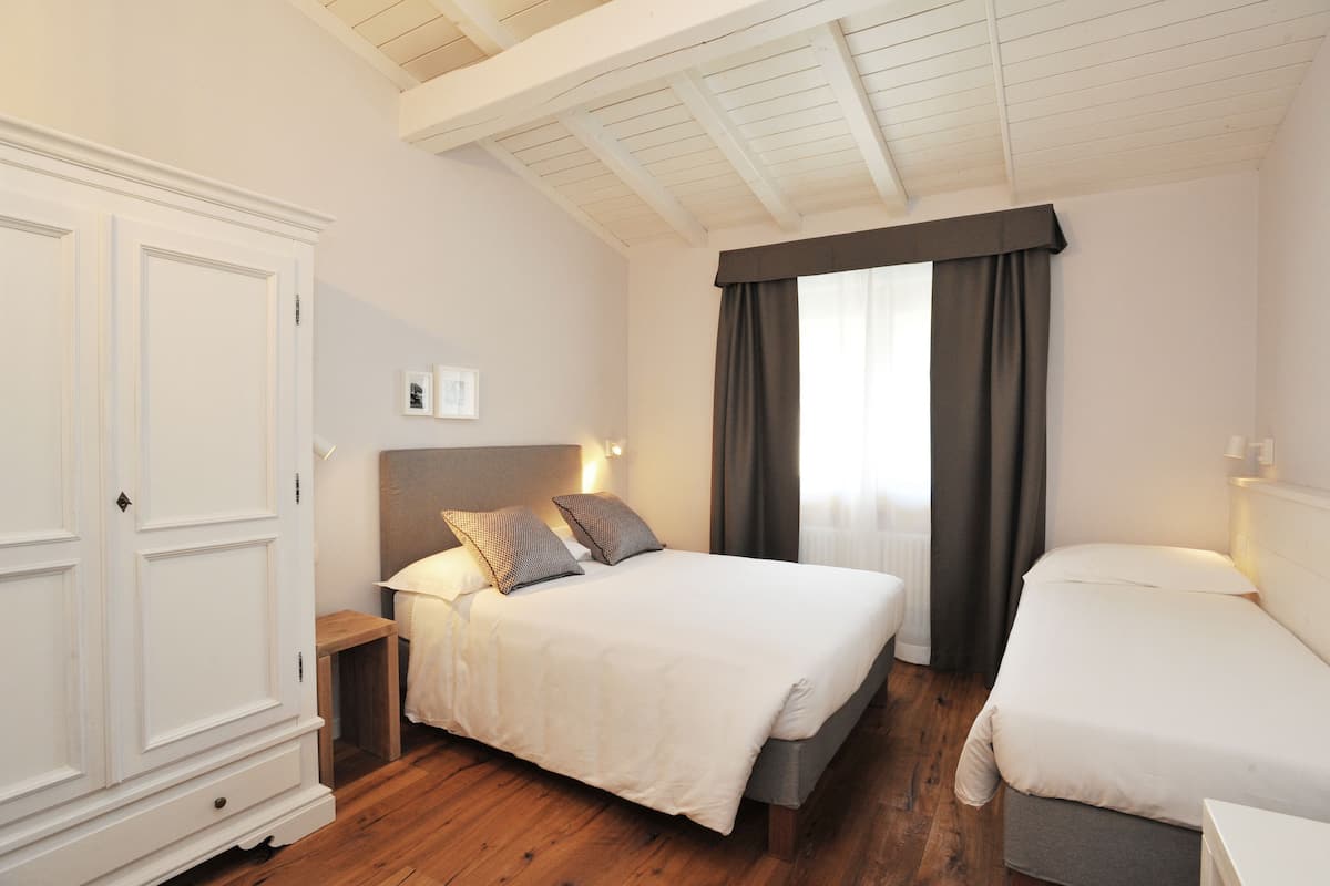 A bedroom with a large bed, a smaller bed, a wardrobe, and a nightstand.