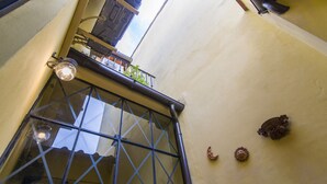 A corner of a building with a window, a metal railing, and a wall-mounted decoration. - Florence Ariento Romantic Apartment (Florence)