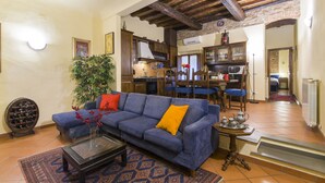 A living room with a blue sofa, a coffee table, and a dining area with blue chairs. - Florence Ariento Romantic Apartment (Florence)