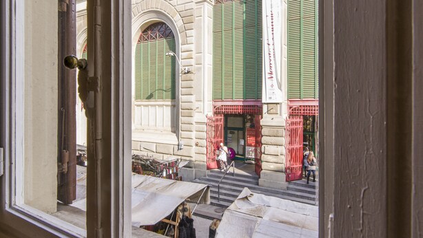 A view through a window of a building with a staircase leading to a door with green shutters. - Florence Ariento Romantic Apartment (Florence)