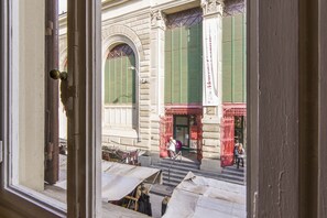 A view through a window of a building with a staircase leading to a door with green shutters. - Florence Ariento Romantic Apartment (Florence)