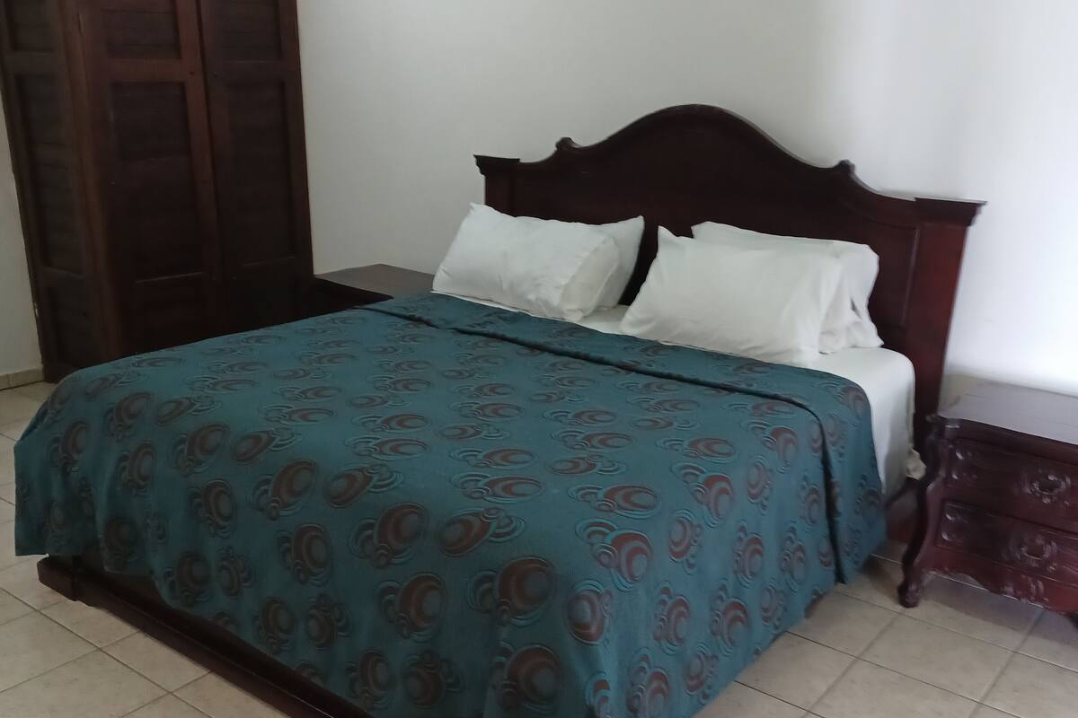 A bedroom with a bed, a wardrobe, and a nightstand.