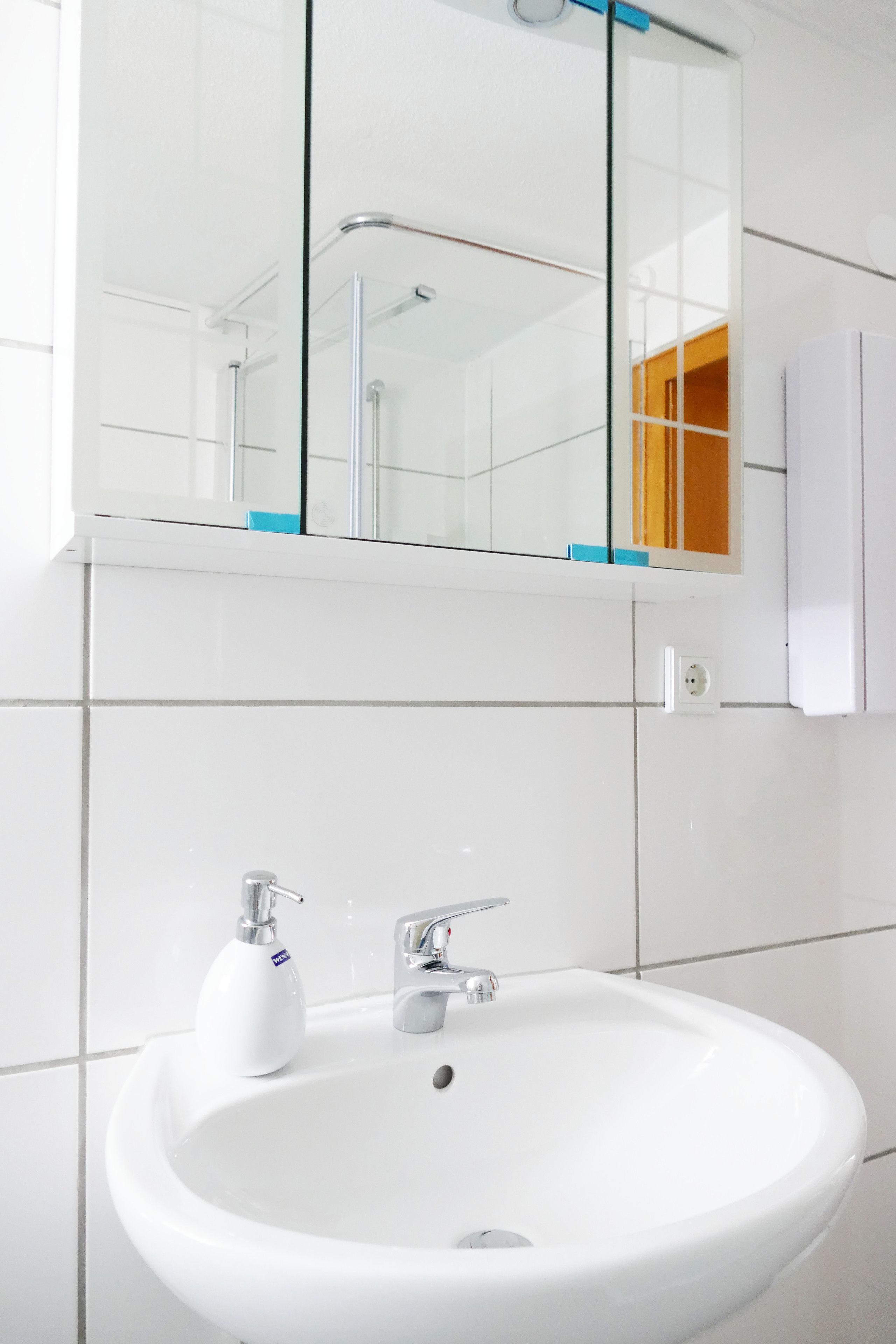 A bathroom with a white sink, a mirror above it, and a glass shower enclosure.