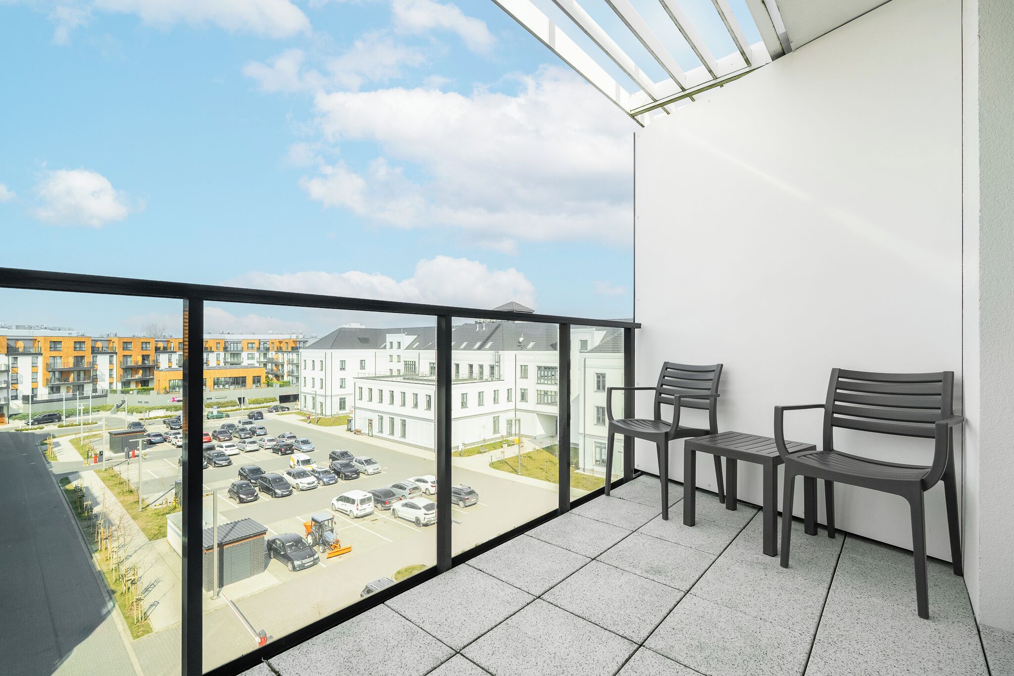 A balcony with a view of a parking lot and buildings.