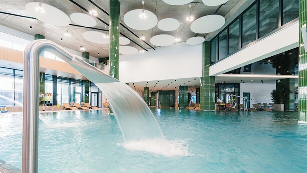 Une piscine intérieure dotée d’un toboggan aquatique, de grandes fenêtres et d’une architecture moderne.