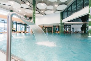 Ein Hallenbad mit Wasserrutsche, großen Fenstern und modernem architektonischem Design.