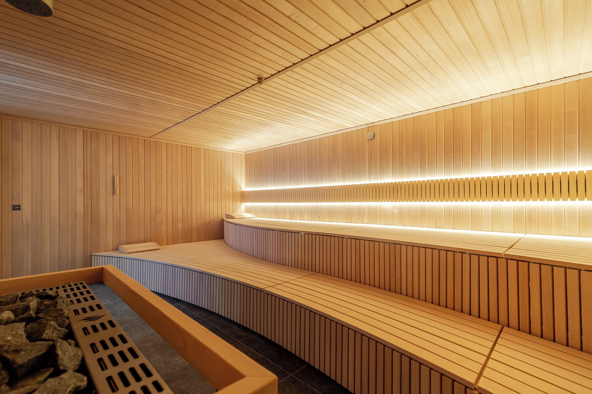 A sauna with wooden benches and a sloped ceiling.