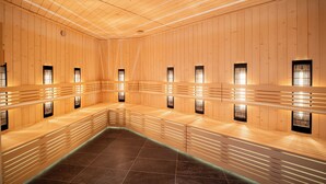 Un sauna aux murs et aux bancs en bois, doté de petites fenêtres et de luminaires fixés au mur.