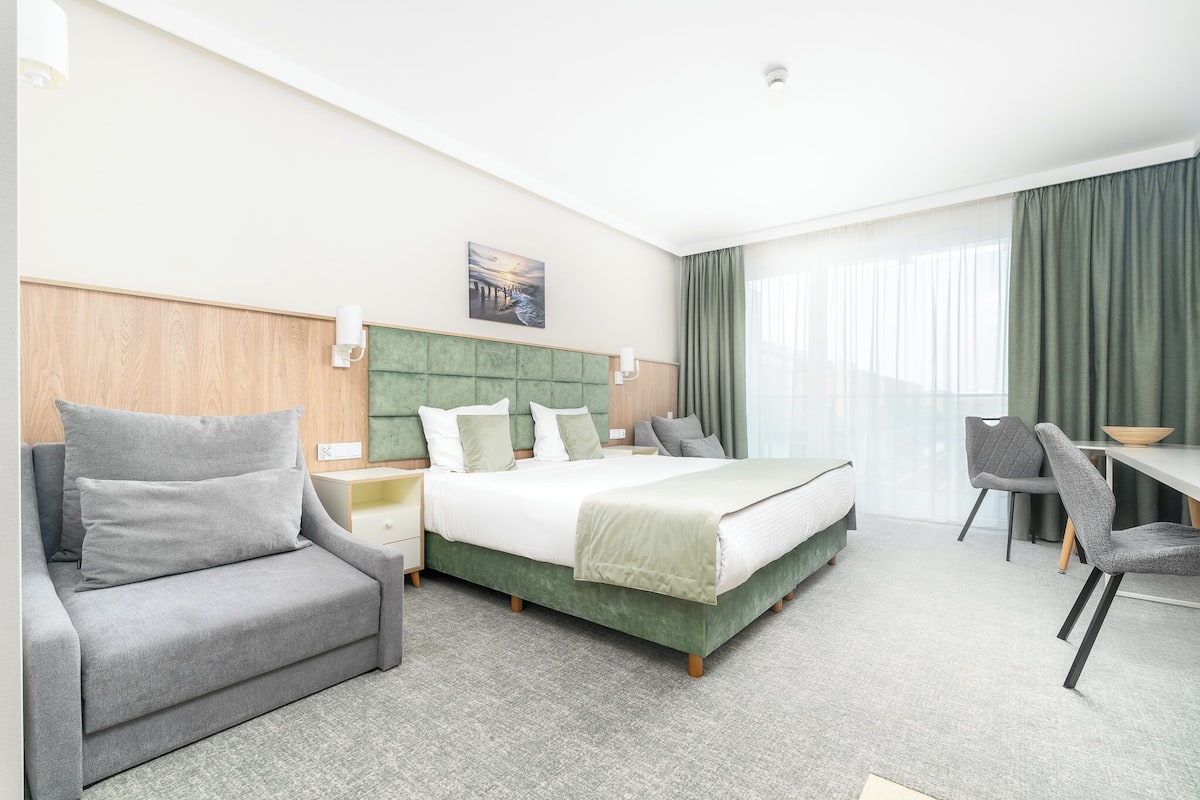 Une chambre d’hôtel avec un lit, un canapé, un bureau et une chaise.
