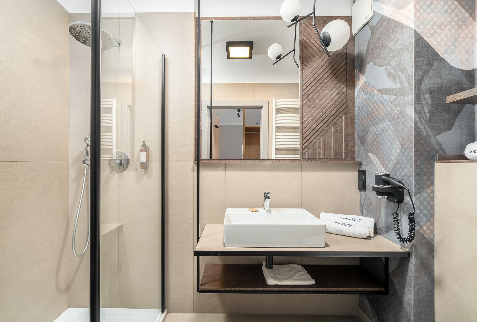 Ein modernes Badezimmer mit einer gläsernen Dusche, einem weißen Waschbecken und einem Spiegel darüber.