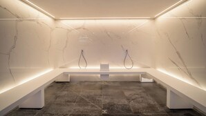 Une salle de bain moderne avec des murs en marbre, un banc et deux pommes de douche.