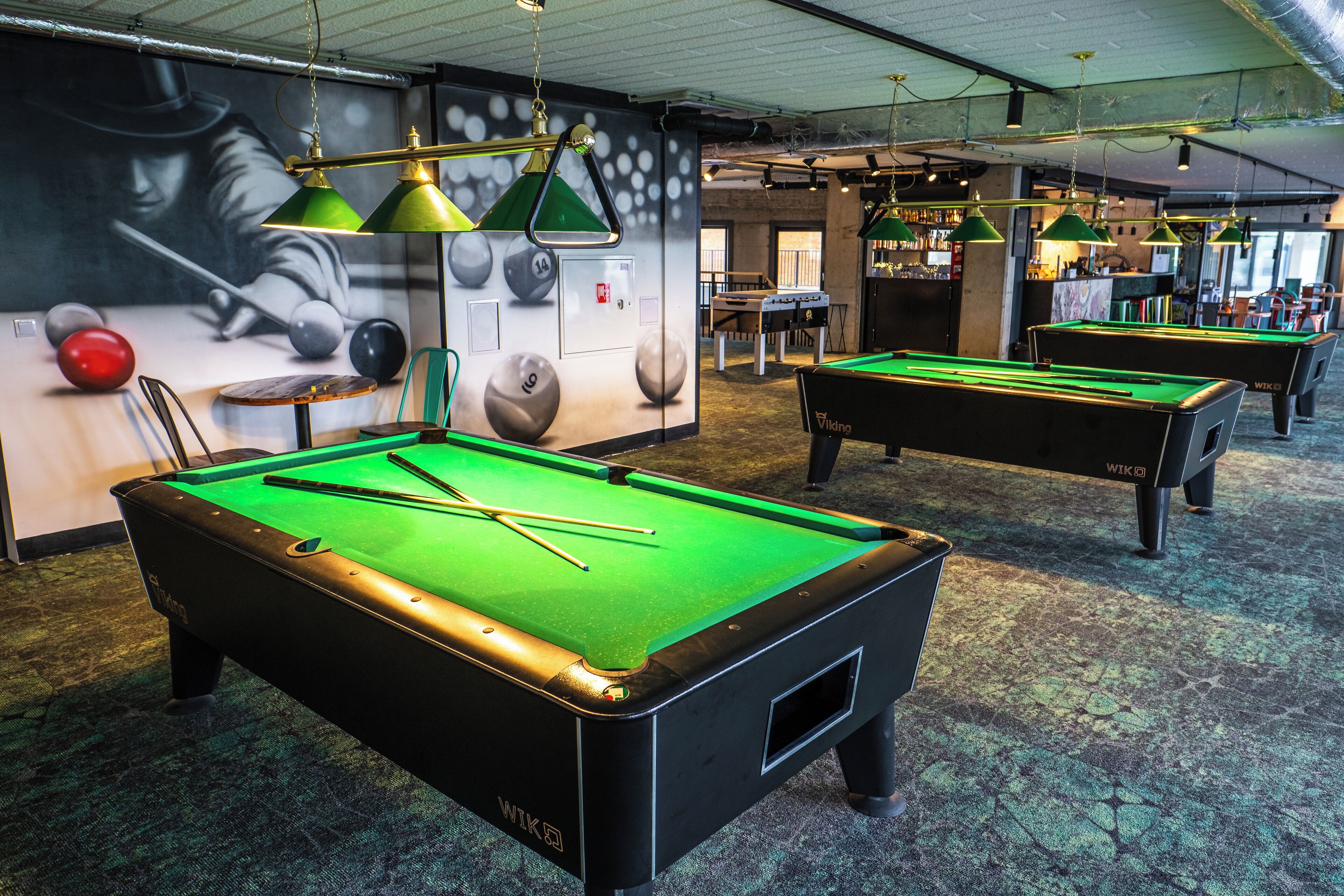 A pool table with a green felt surface, a billiard cue, and a pool ball.
