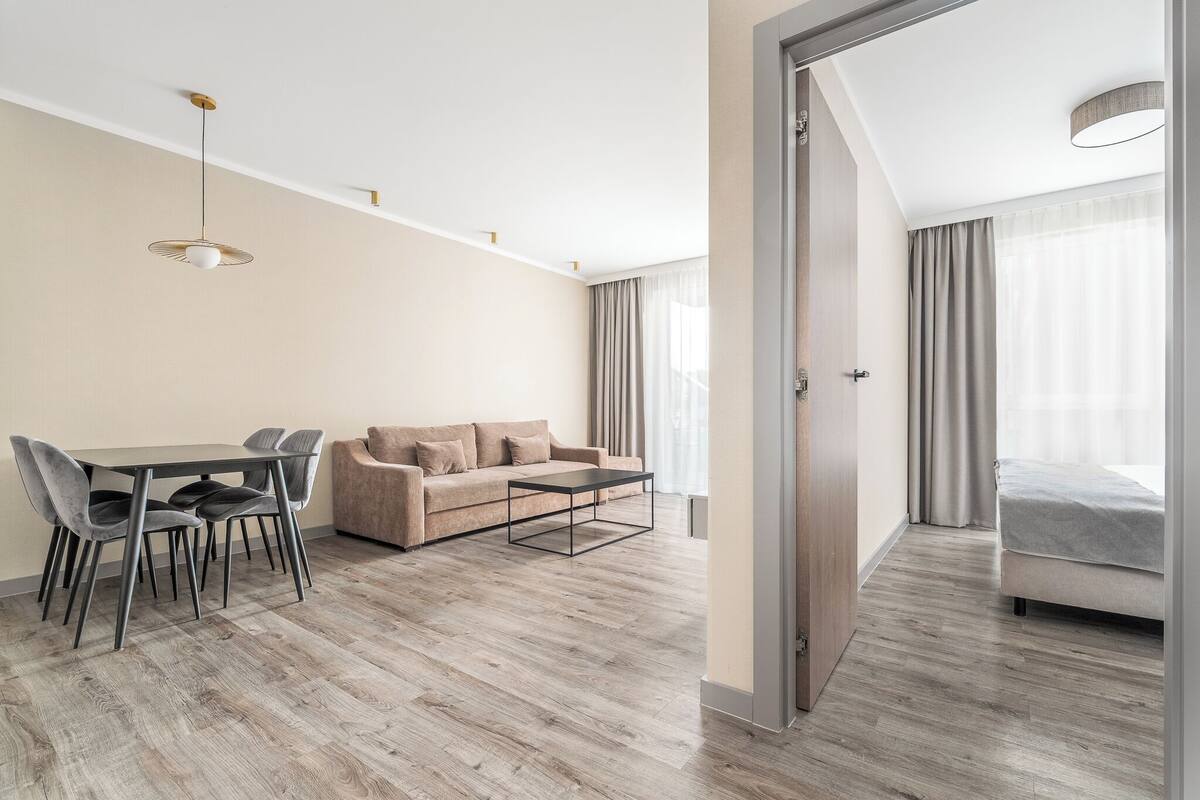 Une chambre d’hôtel moderne avec un plancher en bois, un canapé, une table à manger avec des chaises et un lit.