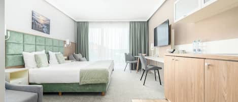 Una habitación de hotel con cama, escritorio, silla, televisor y armario.
