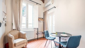 A room with a beige armchair, a blue chair, a small round table with a plate and cutlery, and a radiator. - Lambertesca Mono (Florence)