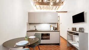 A compact kitchen with a dining area, a built-in oven, and a flat-screen TV. - Lambertesca Mono (Florence)