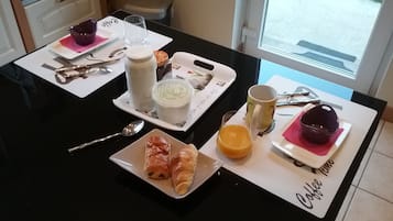 Una mesa de desayuno con croissants, un vaso de jugo de naranja, una taza y un plato de comida.