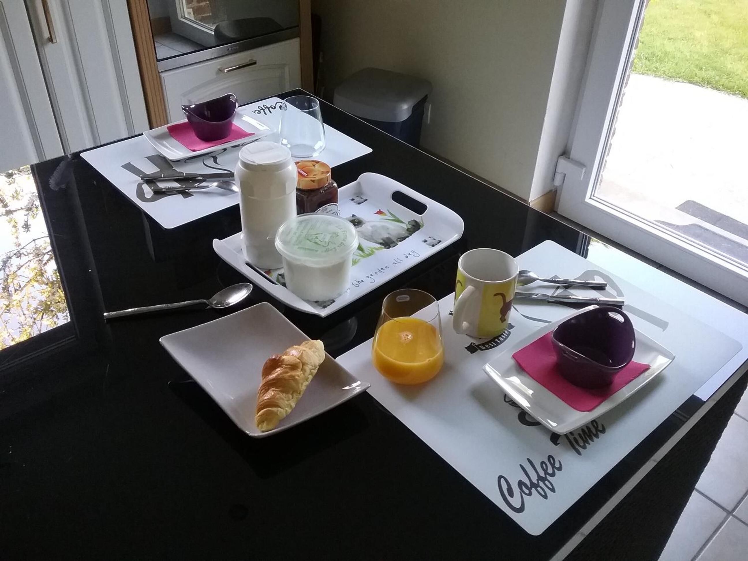 A breakfast table with croissants, orange juice, coffee, and a muffin.