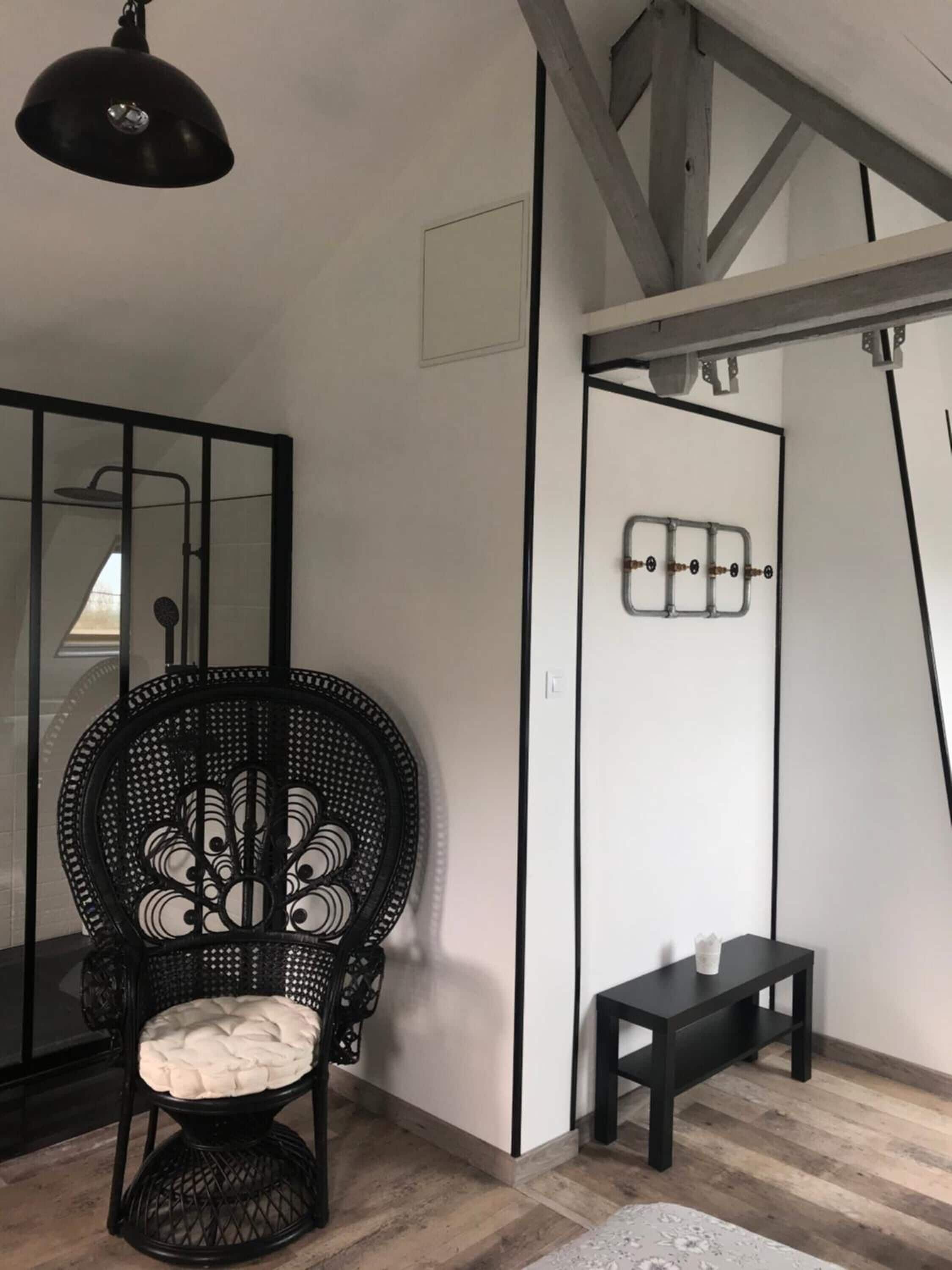 A modern interior with a black wicker chair, a small black table, and a mirror.