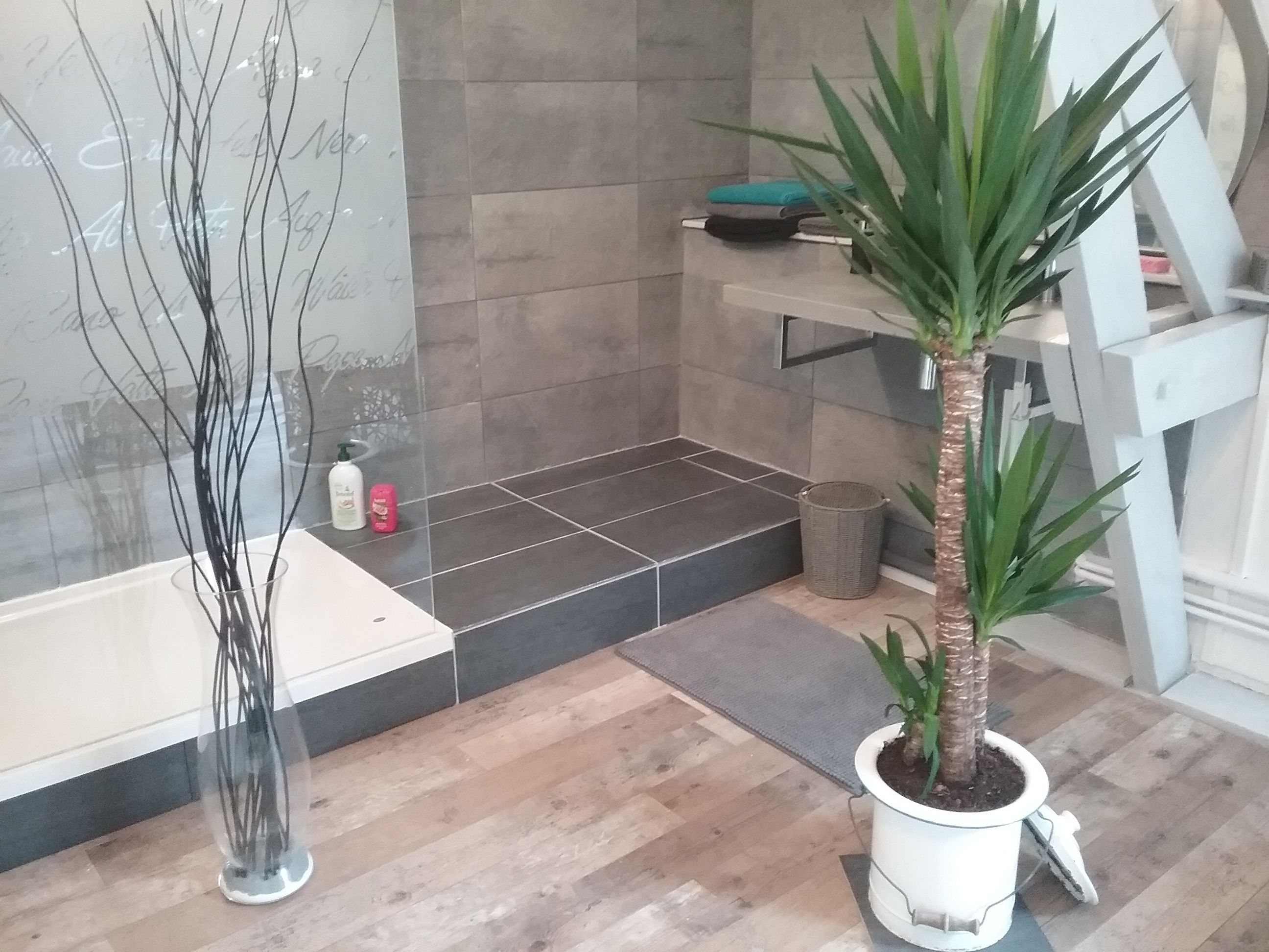 A bathroom with a bathtub, a shower area, a potted plant, and a wicker basket.