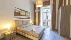 A bedroom with a bed, bedside table, lamp, and a view of the outside balcony. - Be Italian Flat Duomo 319 (Naples)
