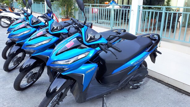 Una hilera de motocicletas azules estacionadas frente a un edificio con un cartel que dice 'Blue Moon'.