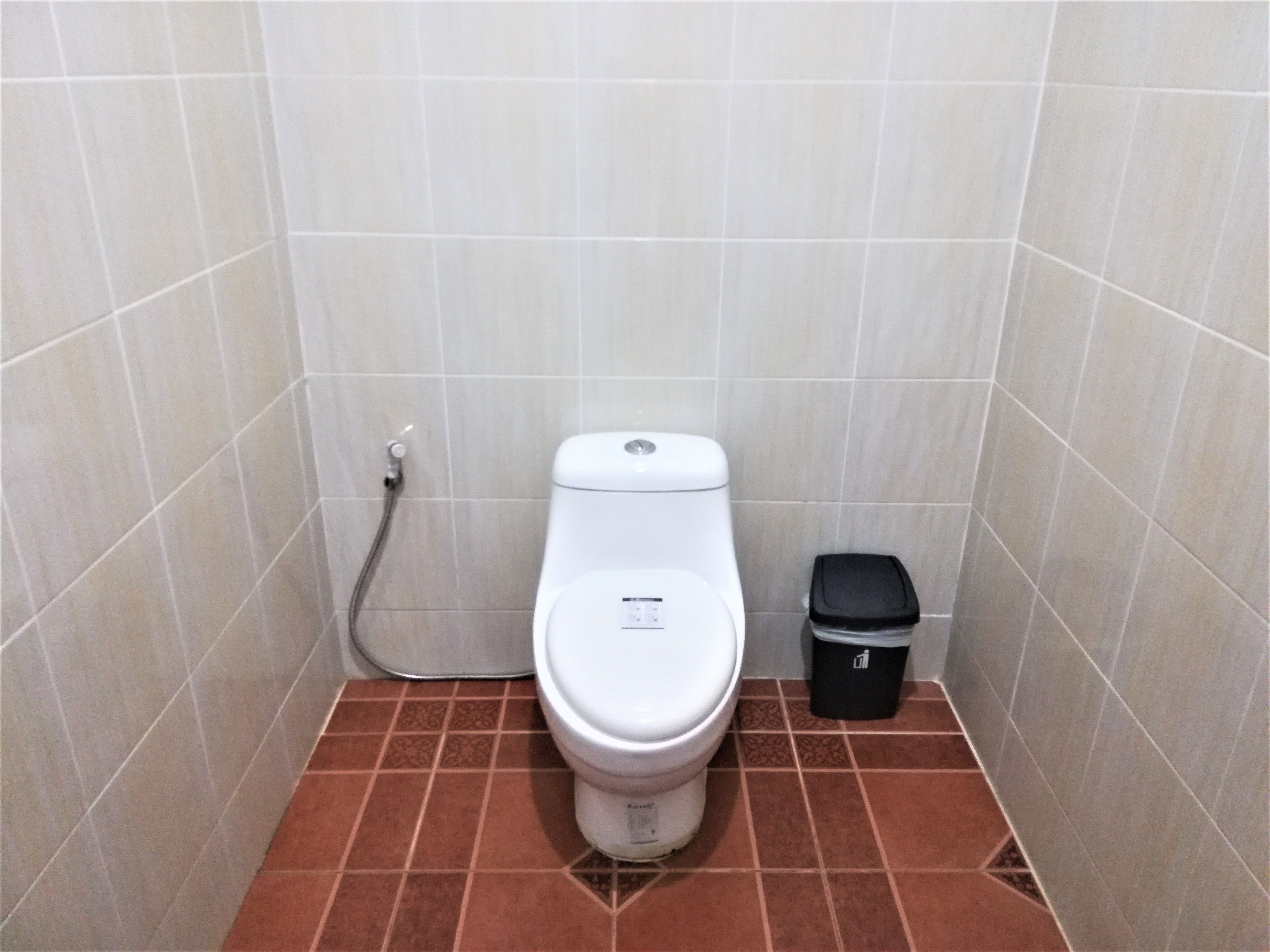 Un baño pequeño con paredes de azulejos, un inodoro y un cubo de basura.