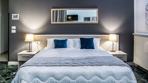 A hotel room with a large bed, two bedside lamps, a flat-screen TV, and a mirror above the bed. - Amarillo (Palermo)