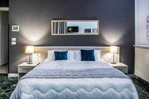 Camera d'hotel con un letto grande, due lampade ai comodini, una TV a schermo piatto e uno specchio sopra il letto.
