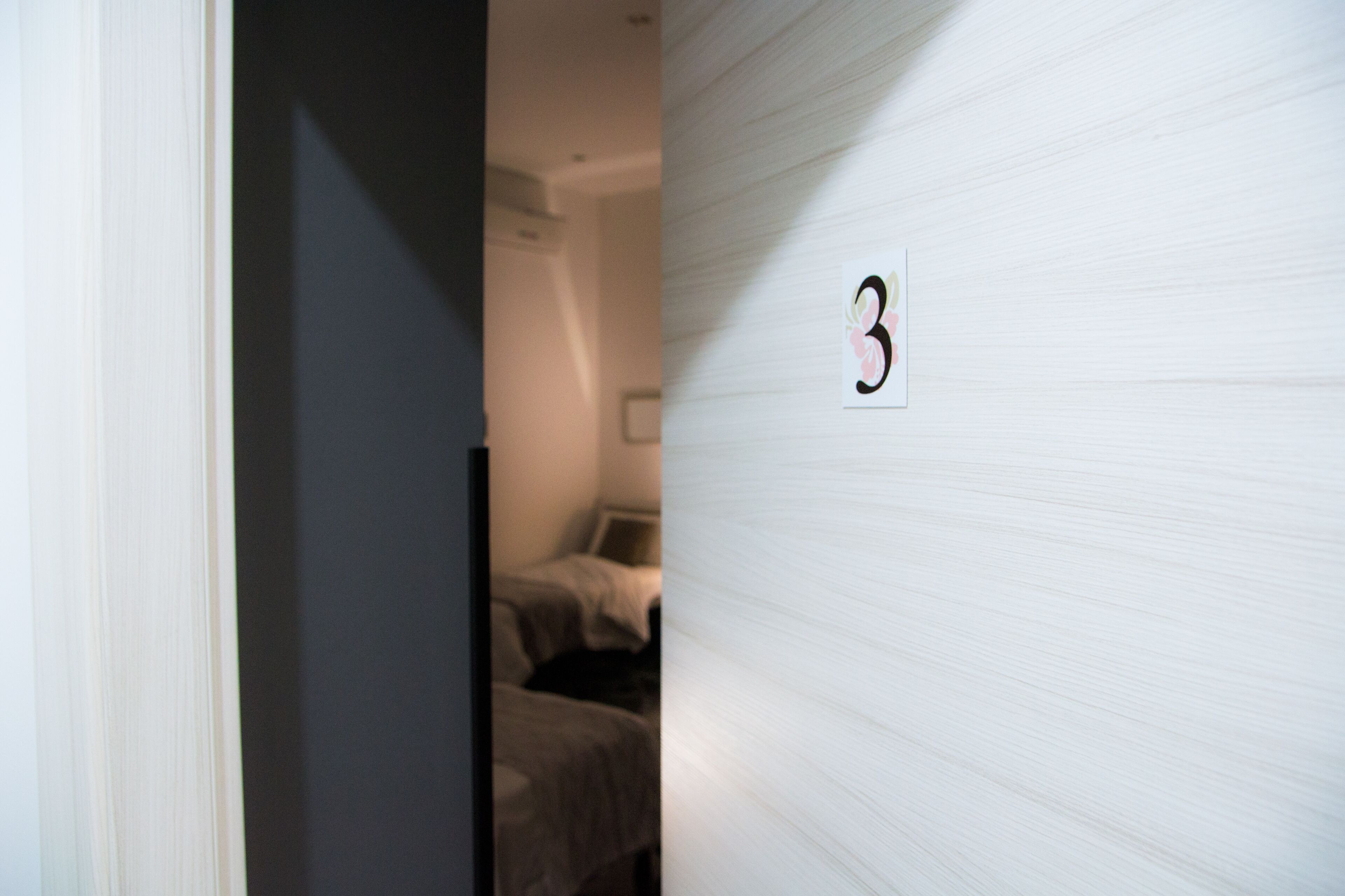 Una habitación con una cama y el número '3' colgado en la pared.