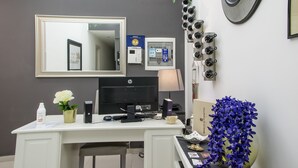 A hotel room with a white desk, a computer, a mirror, a clock, and a plant. - Amarillo (Palermo)