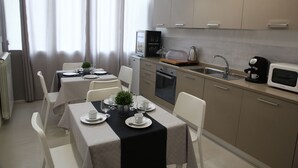 A modern kitchen with a dining area, featuring a microwave, coffee maker, and a small refrigerator. - Amarillo (Palermo)