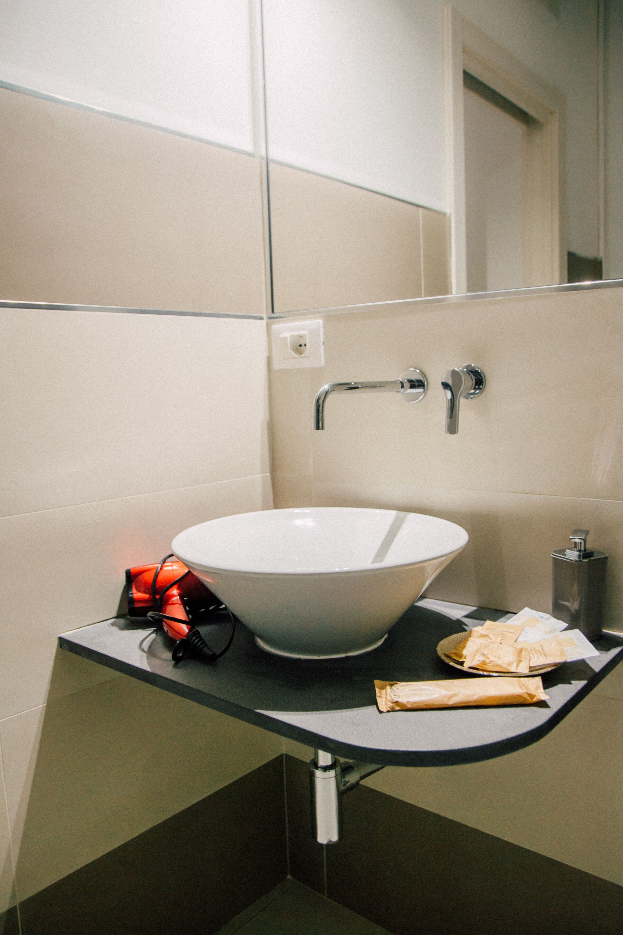 Une salle de bain avec un lavabo blanc, un distributeur de serviettes et une petite poubelle.