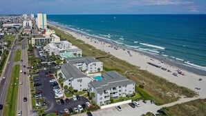 Un hotel costero con varias edificaciones, acceso directo a la playa y un estacionamiento.
