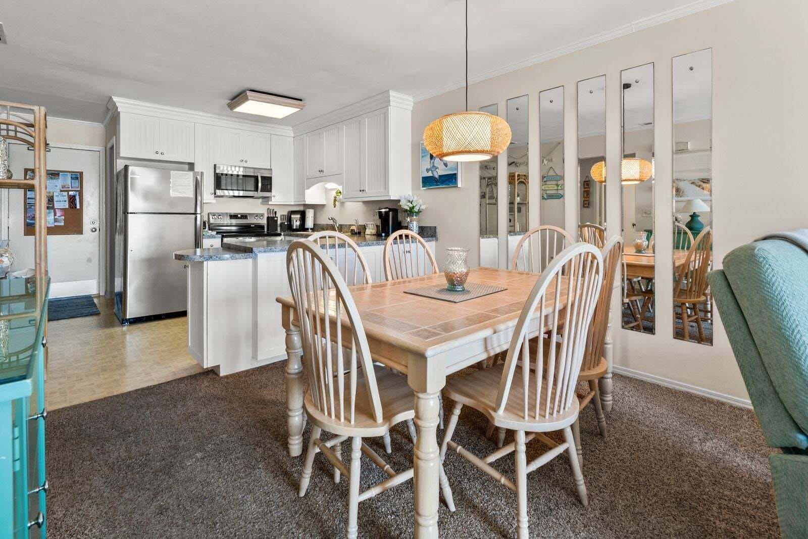A modern kitchen with white cabinetry, stainless steel appliances, and a dining area with a wooden table and chairs.
