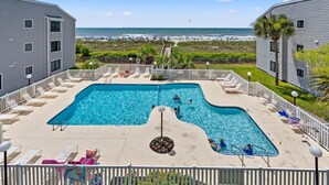 A swimming pool with a view of the beach, surrounded by lounge chairs and a white fence. - Sea Cloisters 303e 2 Bedroom Condo by RedAwning (North Myrtle Beach)