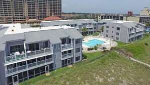 A multi-story residential building with a rooftop pool and a large building in the background. - Sea Cloisters 303e 2 Bedroom Condo by RedAwning (North Myrtle Beach)