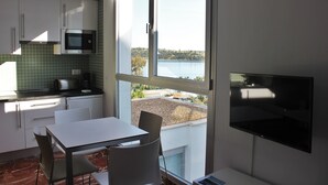 A kitchen with a dining area, a TV, and a view of a lake. - Apartamentos Embalse de Orellana (Orellana la Vieja)